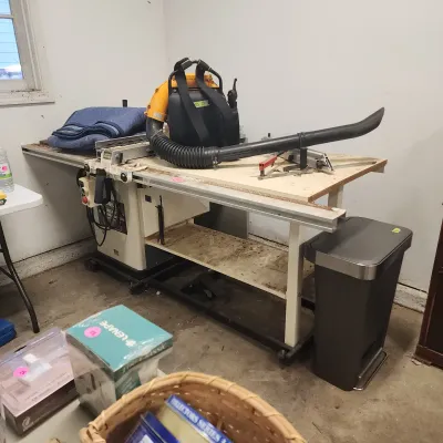 Sale Photo Thumbnail #151: Delta stationary table saw setup with attached outfeed work table, featuring an orange gas-powered backpack leaf blower resting on top.