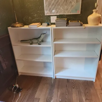Sale Photo Thumbnail #106: Pair of modern white laminate three-tier bookcases displaying a lizard figurine and assorted books.