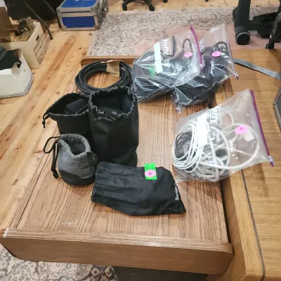 Collection of camera gear accessories including protective drawstring pouches, bundled cables, and items organized in plastic storage bags.
