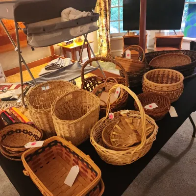 Collection of woven wicker and splint baskets in various sizes, shapes, and natural tones arranged on a table.