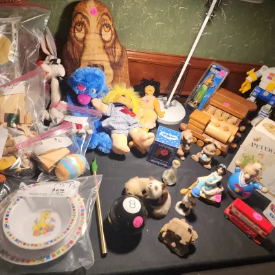 Collection of vintage toys and knick-knacks, including plush dolls, wooden trains, a magic 8-ball, small figurines, and a Sesame Street...