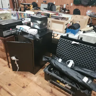 Sale Photo Thumbnail #101: Collection of media equipment including an open foam-lined hard case with stands, a black media cabinet, vinyl record crates, and vintage electronics.