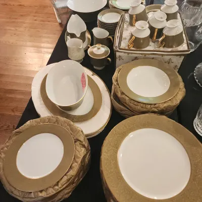 Sale Photo Thumbnail #109: Extensive fine china dinnerware set with wide textured gold borders, including plates, teacups, serving bowls, creamers, and protective storage cases.