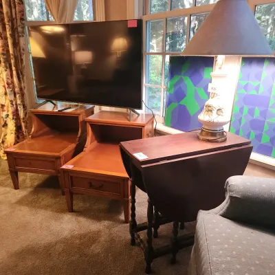 A collection of furniture including a pair of mid-century step-back end tables supporting a flat-screen TV, alongside a wooden drop-leaf...