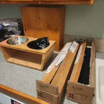 Sale Photo Thumbnail #143: Elevated wooden double pet diner feeder stand alongside two long cardboard shipping boxes marked at $15 each.
