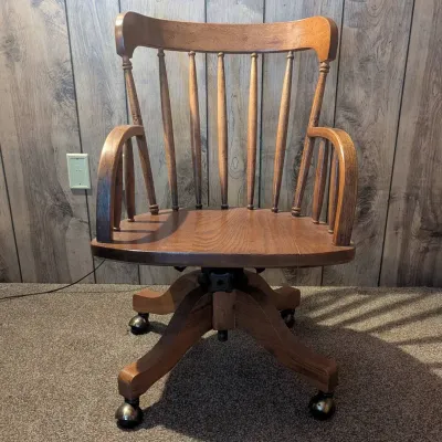 Sale Photo Thumbnail #125: Vintage oak swivel office chair with a spindle backrest and metal ball casters.