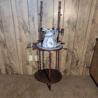 Sale Photo Thumbnail #86: Vintage dark wood washstand featuring twisted spindle legs and side towel bars, paired with a blue and white floral ceramic pitcher and basin set.