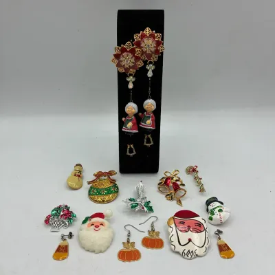 Sale Photo Thumbnail #193: Collection of festive holiday jewelry, including enamel Christmas brooches, dangle earrings with Mrs. Claus figures, and pumpkin-themed pieces.