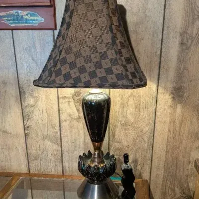Sale Photo Thumbnail #52: Vintage table lamp featuring a dark splatter-finish urn base with brass accents, paired with a checkered patterned lampshade.