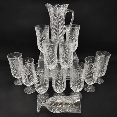 Sale Photo Thumbnail #32: Vintage cut crystal glassware set featuring a tall pitcher, highball glasses, and footed iced tea glasses in a matching palm or feather motif.