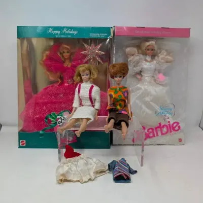Sale Photo Thumbnail #151: Collection of vintage Barbie dolls, including a NIB 1990 Happy Holidays Barbie, a NIB Wedding Fantasy Barbie, and two loose dolls seated on a display riser with extra doll clothing.
