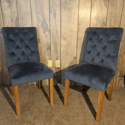 Sale Photo Thumbnail #119: Pair of contemporary dining chairs featuring dark blue velvet upholstery with button-tufted backs and natural wood legs.
