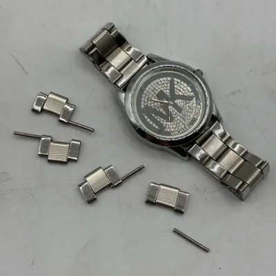 Sale Photo Thumbnail #204: Michael Kors silver-tone wristwatch featuring a rhinestone-embellished MK logo dial, displayed alongside extra band links and pins.