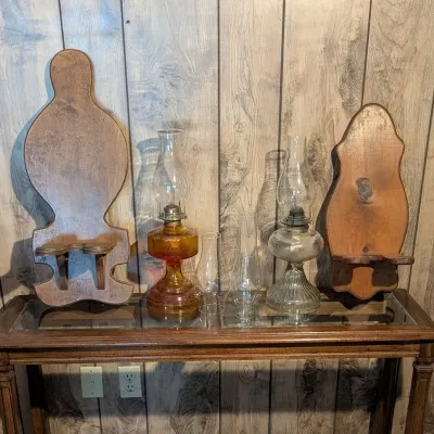 Sale Photo Thumbnail #50: Collection of vintage items including an amber glass oil lamp, clear glass oil lamp, extra glass chimneys, and two wooden sconces.