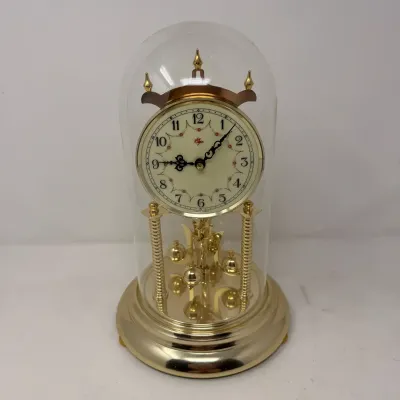 Sale Photo Thumbnail #29: Vintage Elgin brass anniversary clock housed under a clear glass cloche dome, featuring a floral-accented dial and rotating pendulum.