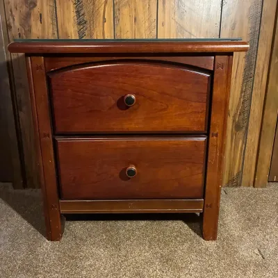 Sale Photo Thumbnail #2: Craftsman-style cherry wood two-drawer nightstand featuring decorative inlay accents, round wooden knobs, and a protective glass top.