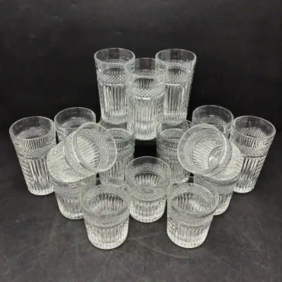 Sale Photo Thumbnail #175: Large set of clear cut glass drinking glasses featuring diamond and fluted panel patterns in highball and lowball sizes.
