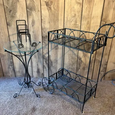 Sale Photo Thumbnail #62: Black wrought iron two-tier rolling utility cart alongside a small glass-topped accent table with scrollwork details.