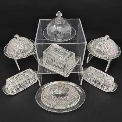 Sale Photo Thumbnail #40: Collection of vintage clear pressed glass and etched glass butter dishes and covered serving pieces, including round dome-topped and rectangular shapes in various starburst and diamond patterns.