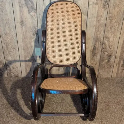 Sale Photo Thumbnail #121: Bentwood rocking chair with woven cane backrest and seat, featuring a dark stained finish showing moderate surface wear.