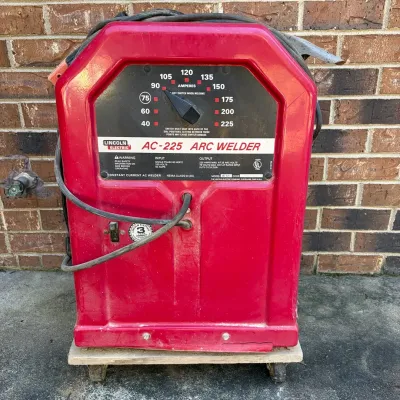Sale Photo Thumbnail #66: Lincoln Electric AC-225 stick arc welder in red metal housing, mounted on a small wheeled dolly base.