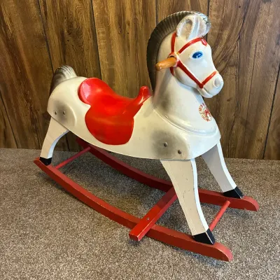 Sale Photo Thumbnail #171: Vintage molded plastic and wood rocking horse with a red seat, red base runners, and wooden hand pegs.