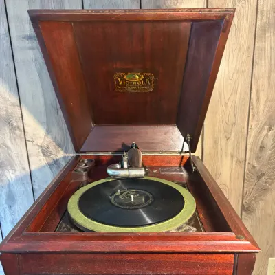 Sale Photo Thumbnail #102: Antique Victrola tabletop phonograph in a mahogany cabinet by Victor Talking Machine Co., featuring a gold decal under the open lid and a turntable with an acoustic reproducer tone arm.