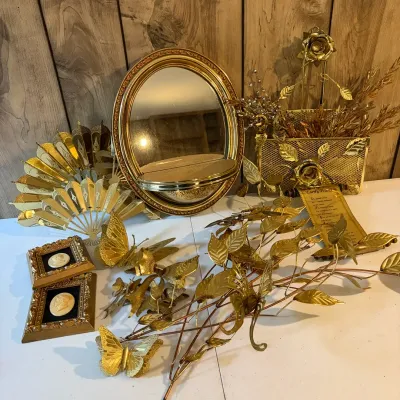 Sale Photo Thumbnail #148: Collection of vintage gold-toned home decor items, including a oval framed mirror, decorative metal fans, butterfly wall accents, and cameo portraits.