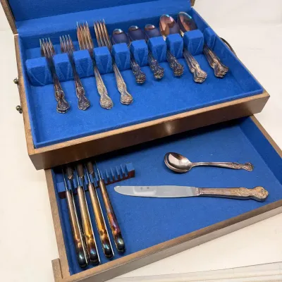 Sale Photo Thumbnail #24: Vintage tarnished silver-plated flatware set with ornate floral handles, stored in a wooden silverware chest with bright blue felt lining.