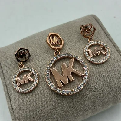 Sale Photo Thumbnail #199: Michael Kors rose gold-tone jewelry set, including a matching pair of drop earrings and a pendant, featuring rhinestone halo circles and MK logo accents.
