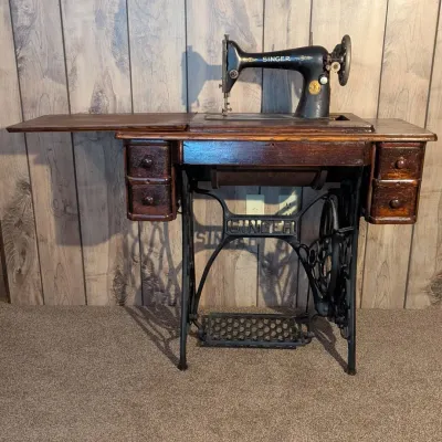 Sale Photo Thumbnail #89: Antique Singer treadle sewing machine set in a dark wood cabinet with side drawers and a cast iron base.