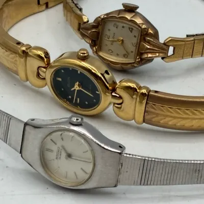 Sale Photo Thumbnail #205: Trio of vintage women's wristwatches, including a gold-tone Bulova, a gold-tone Elgin with a black dial, and a silver-tone Seiko Quartz.