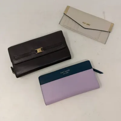 Sale Photo Thumbnail #21: Collection of three women's designer wallets, including a dark brown Etienne Aigner leather clutch, a colorblocked Kate Spade zip-around wallet, and a cream-colored Nine West envelope wallet.