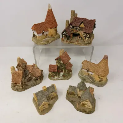 Sale Photo Thumbnail #28: Collection of seven miniature resin cottage sculptures, featuring detailed English village-style architecture with thatched and shingled roofs.