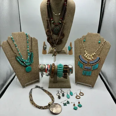 Sale Photo Thumbnail #192: Collection of Southwestern and bohemian style costume jewelry, including faux turquoise statement necklaces, beaded bracelets, rings, and dangle earrings displayed on burlap stands.