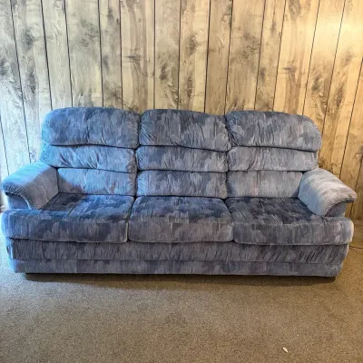 Sale Photo Thumbnail #134: Plush 1980s or 1990s three-cushion sofa upholstered in blue patterned velour, set against wood paneling.