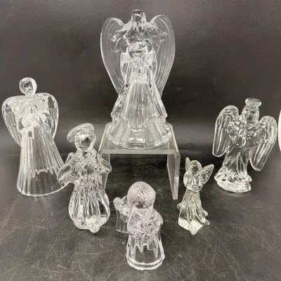 Sale Photo Thumbnail #34: Collection of six clear pressed glass angel figurines in assorted sizes and poses, displayed on a black backdrop with an acrylic riser.