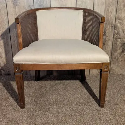 Sale Photo Thumbnail #87: Vintage barrel armchair featuring a dark wood frame with woven cane back, fluted legs, and off-white fabric upholstery.