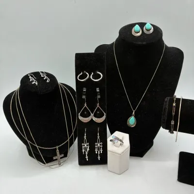 Sale Photo Thumbnail #195: Collection of sterling silver and turquoise fine jewelry, including a cross pendant necklace, turquoise cabochon pendant and stud set, dangle earrings, and a ring displayed on velvet busts and stands.