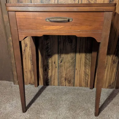 Sale Photo Thumbnail #44: Mid-century modern wooden sewing machine cabinet with a faux drawer front and brass pull handle.