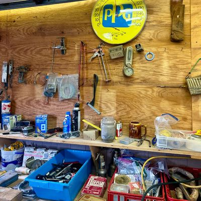 Sale Photo Thumbnail #16: Workshop wall layout featuring a vintage bright yellow PPG thermometer, hand tools, hardware supplies, and storage bins on wood shelving.