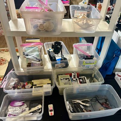 Sale Photo Thumbnail #41: Assorted household items and office supplies organized in plastic storage bins, including seashells, small electronics, hole punches, and office stationery.