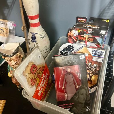 Sale Photo Thumbnail #53: Collection of mixed collectibles, including a clear bin filled with boxed Star Wars and Marvel action figures, a packaged Ronald McDonald sugar cookie, an autographed bowling pin, and a pirate mug.