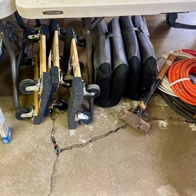 Sale Photo Thumbnail #18: Collection of workshop and moving supplies, including carpeted furniture dollies, an orange air hose, heavy-duty extension cords, a sledgehammer, and a Haul-Master aluminum work platform.