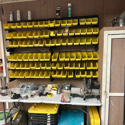 Sale Photo Thumbnail #29: Wall-mounted storage rack with yellow plastic organizer bins set above a worktable holding power tools and supplies.