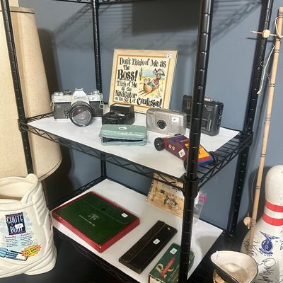 Sale Photo Thumbnail #56: Black wire utility shelving unit displayed with vintage cameras, small novelties, collectable figurines, and various home decor items.