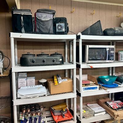 Sale Photo Thumbnail #27: White plastic utility shelving units filled with various household goods, including a meat slicer, slow cooker buffet, microwave, and small appliances.