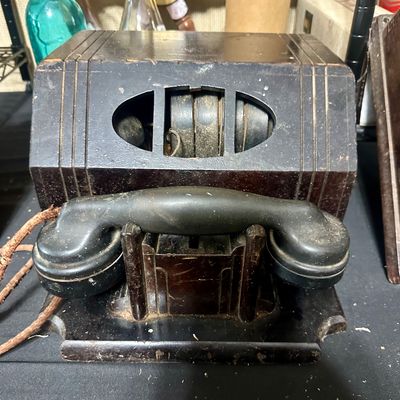 Sale Photo Thumbnail #67: Vintage Art Deco wood and Bakelite desk telephone with direct-dial wheels, showing surface wear and frayed cloth cordage.