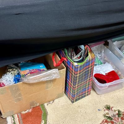 Sale Photo Thumbnail #38: Assorted holiday gift wrap accessories and Christmas decorations stored in plastic totes and cardboard boxes underneath a table.