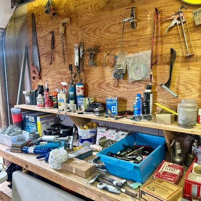 Sale Photo Thumbnail #11: Workshop workbench organized with hand tools, caulking guns, hardware supplies, and vintage boxed accessories.